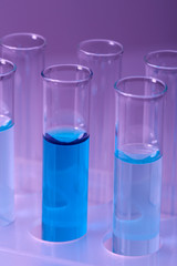 Test-tubes with blue liquid on purple background