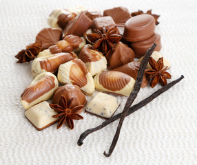 Different kinds of chocolates with spices on white background