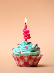 Delicious birthday cupcake on table on beige background