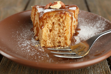 Half eaten delicious cake piece on plate on wooden table