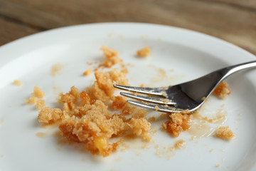 Dirty empty plate with fork on wooden table