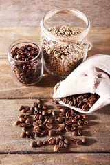 Coffee beans in fabric bag and glass jars on wooden background