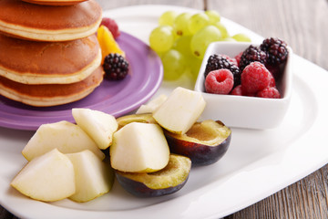Pancake with fruits and berries on plate on wooden table