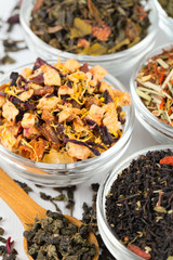 assortment of dry tea in glass bowls on wooden surface