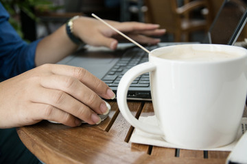 man with a cup of coffee working on his laptop