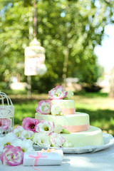 Beautiful wedding cake with flowers on table, outdoors