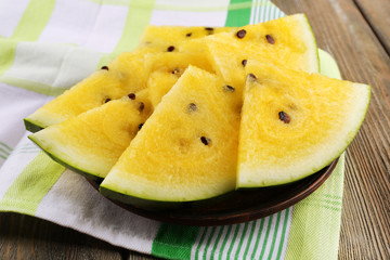 Slices of yellow watermelon on napkin on wooden background
