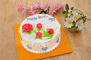 Fototapeta na wymiar Cream cake with rose on the wooden table