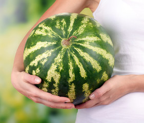 Woman holding watermelon on bright background