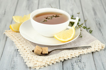 Cup of tasty herbal tea with thyme and lemon on wooden table