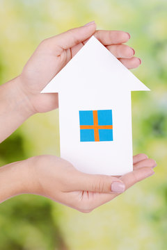 Woman hands holding paper house on bright background