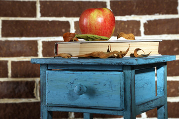 Apple with books and dry leaves