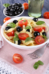 Fototapeta na wymiar Spaghetti with tomatoes, olives and basil leaves