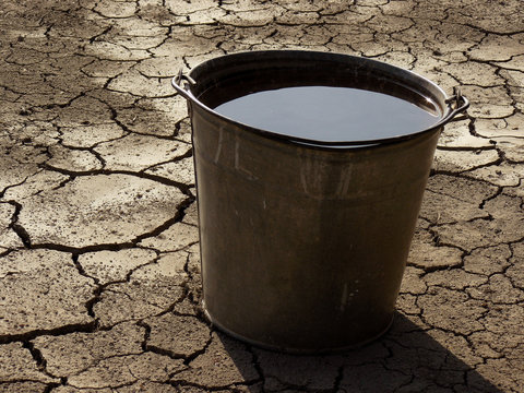 bucket full of water on dry soil background