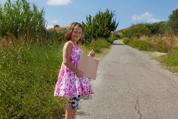 little girl hitchhlikes on the road in the nature