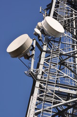 Telecommunication tower with antennas against the blue sky