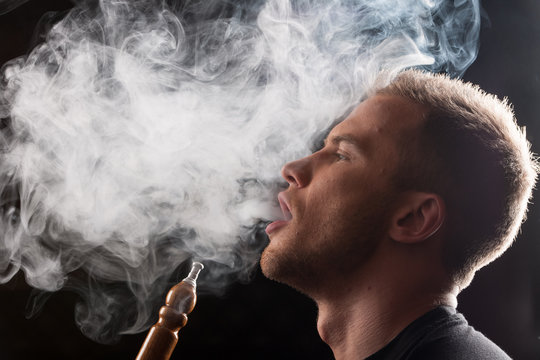 Close-up of man smoking traditional hookah pipe.