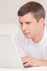 Man lying in bed with his laptop.