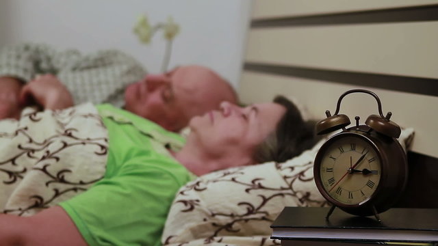 Senior couple laying in bed and peacefully sleeping