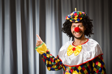Funny clown in humorous concept against curtain
