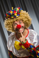 Funny clown in humorous concept against curtain