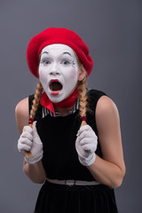 Waist-up portrait of young mime girl showing something