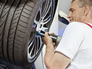 Motor mechanic is changing a tyre with new alu rim