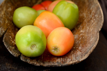 Different varieties of tomatoes on wooden background.