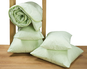 greens twisted blanket and pillows on a shelf isolated on white