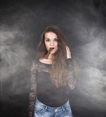 girl smokes cigar in a cloud of fog