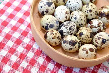 Quail eggs in a birch bark bast basket on a checkered background