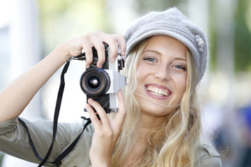Trendy girl taking pictures with vintage camera
