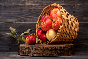 Red apples in basket on wooden background