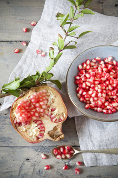 half pomegranate with grains on bowl on wooden table