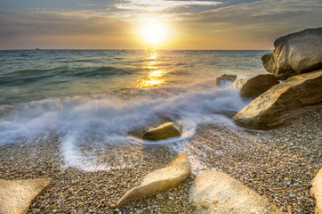 a frozen moment wave enveloping the stone on the seashore