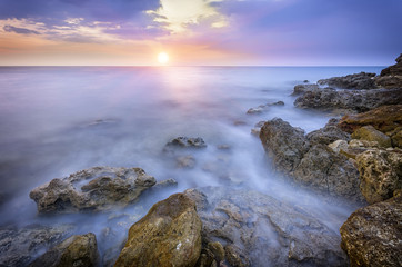 Fototapeta na wymiar coast with sharp stones with view of the setting sun