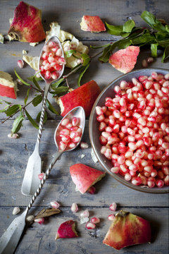 pomegranate grains on bowl with two silver spoon full of grains