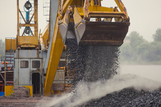 Yellow heavy excavator and bulldozer unloading road metal during