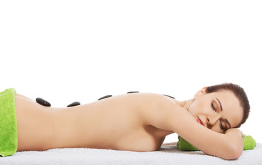 Fototapeta premium Girl on a stone therapy, hot stone massage