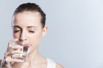 Beautiful girl drinks pure water from a glass