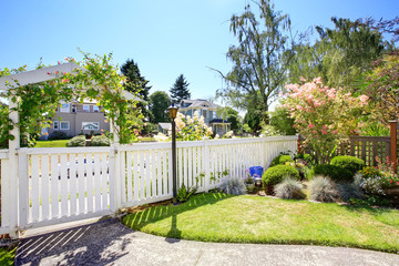 Front yard with white fence and landscape