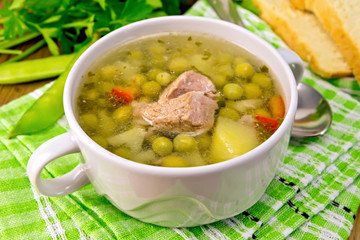 Soup from green peas with meat on green napkin