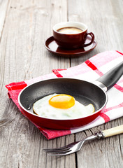 Fried egg in a frying pan, on an old wooden table