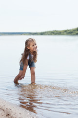 Cheerful little girl playing in lake