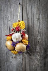 Braided bunch with onions, garlic and flowers, on wooden backgro