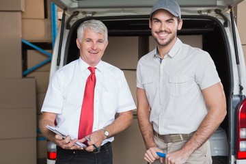 Warehouse manager and delivery driver smiling at camera
