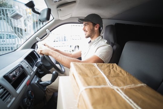 Delivery driver driving van with parcels on seat