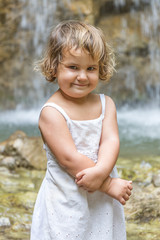 cute smiling toddler child girl on waterfall background