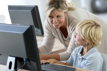 Teacher with schoolboy studying on computer