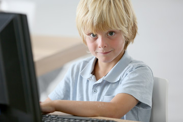 Portrait of school boy sitting in front of computer